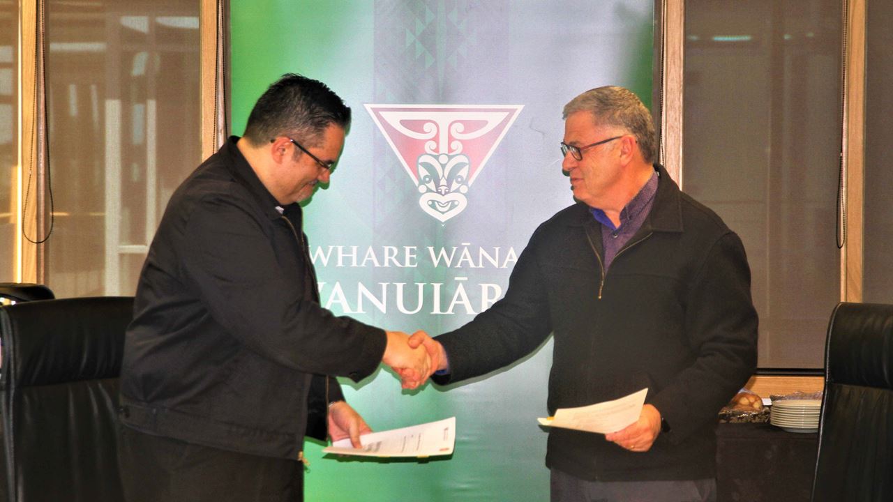 Te Whare Wānanga o Awanuiārangi Council Chairperson Hon. Justice Layne Harvey (left) and Rau Ora, Hospice Eastern Bay of Plenty Chief Executive Peter Bassett (right) shake hands after signing a memorandum of understanding that aims to bring more palliative care nurses to the Eastern Bay of Plenty.